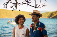 Hombres sonriendo con el mar detrás