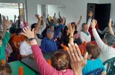 un grupo de adultos mayores están reunidos al rededor de una mesa