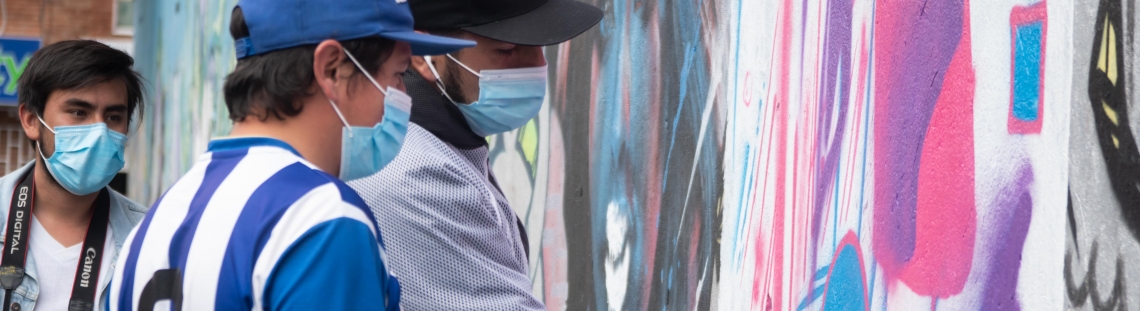 Laboratorista enseña a joven acerca de la pintura de aerosol creando arte en un muro