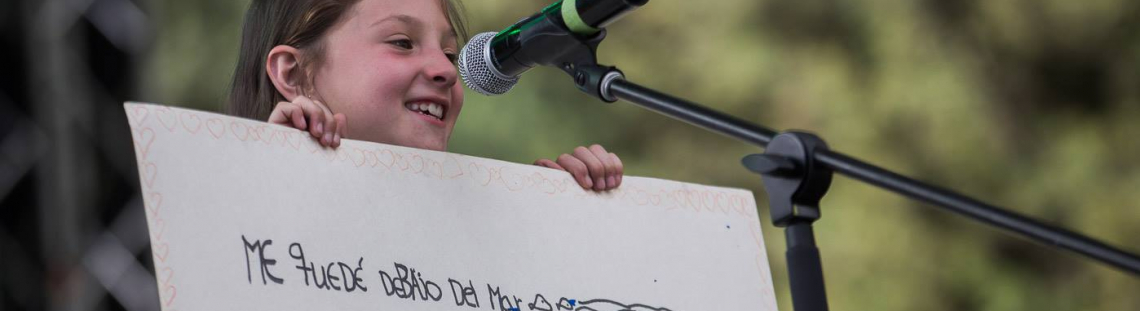 Niña con cartel escrito que participa en una actividad del Programa Crea.