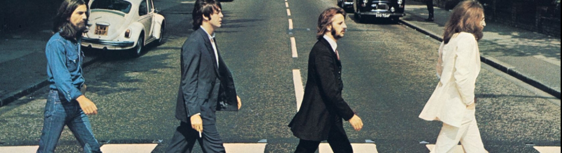 Integrantes de The Beatles caminando sobre la zebra en una calle. 