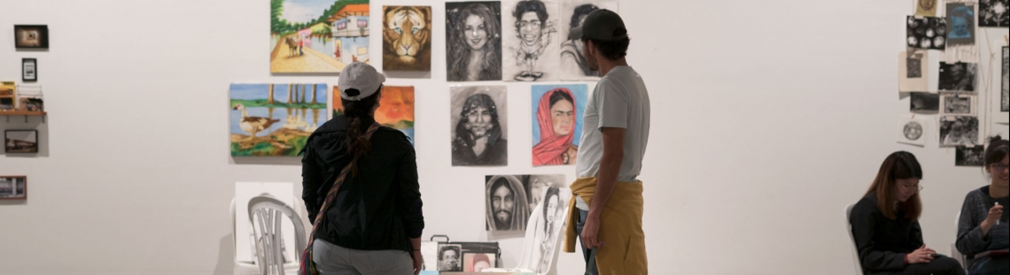 Dos personas y un perro admiran las obras en un stand de las Ferias Locales de Artes en La Candelaria