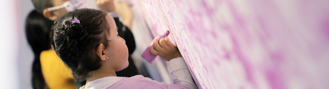 Niños escribiendo con crayola sobre una pared.