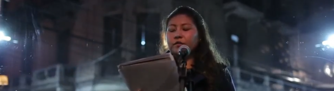 Joven mujer leyendo un texto en una calle durante la noche.