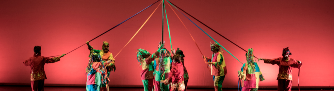 Grupo de bailarines con  lazos de colores entrelazados en el escenario