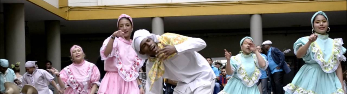 Mujeres bailando y un hombre entre ellas vestido de blanco