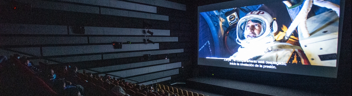 Sala oscura de Cinemateca con proyección de astronauta de fondo. 