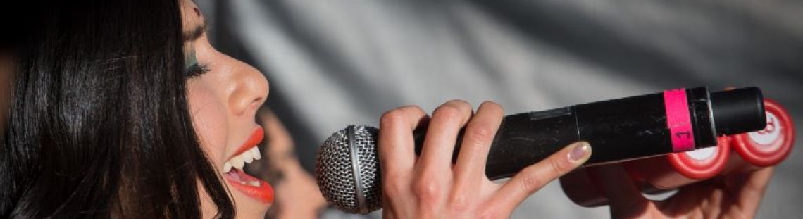 Mujer cantando con micrófono en mano. Fotografía: Carlos Lema. 