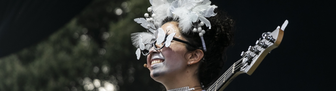 Mujer vestida y maquillada de blanco tocando guitarra