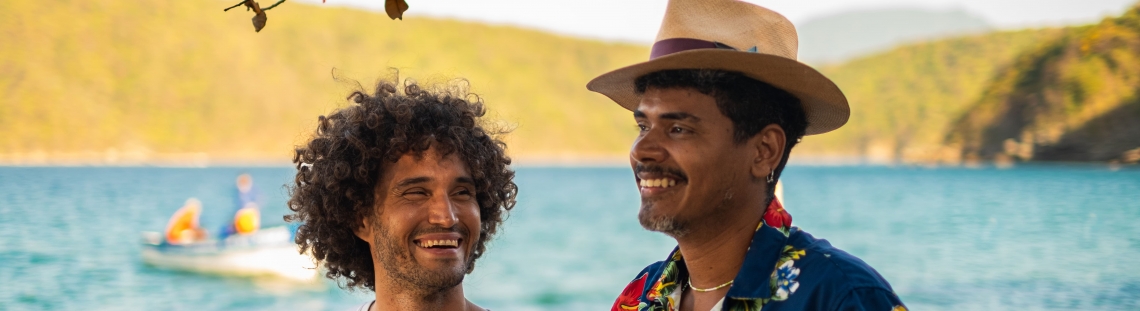 Hombres sonriendo con el mar detrás