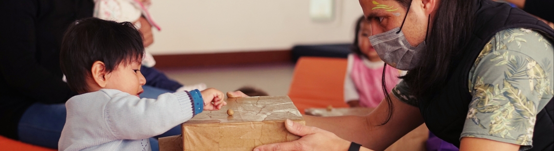 Niños jugando con una caja y un artista del Programa Nidos