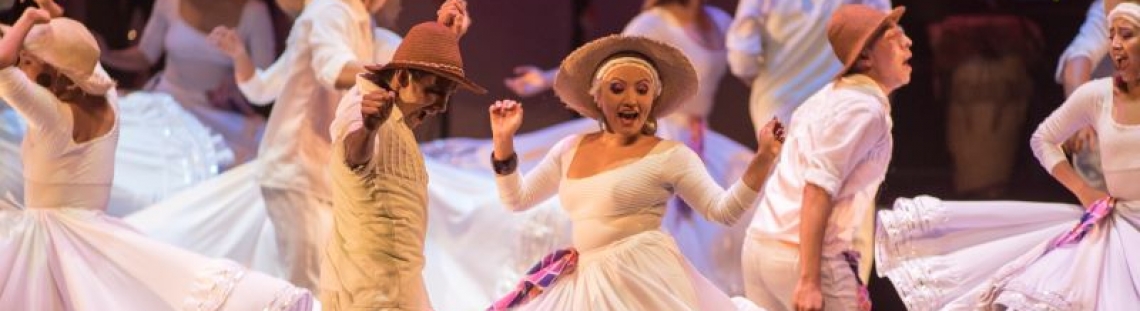 Dos personas bailando en el escenario con trajes típicos colombianos.