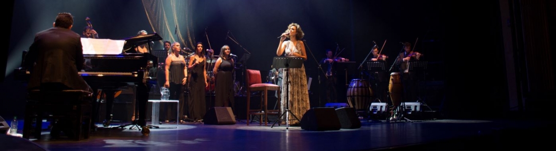 Mujer cantando y un grupo de hombres acompañando su espectáculo