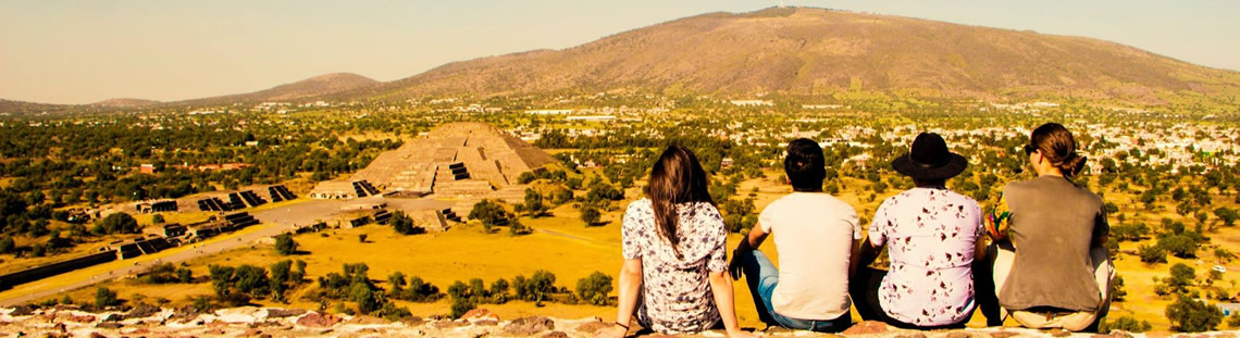 Miembros de la agrupaciónm La Sonidera en un escenario natural, sentados dando la espalda a la cámara