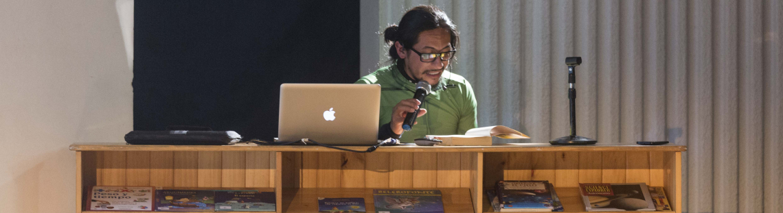 Hombre en una bibliotreca leyendo para el público