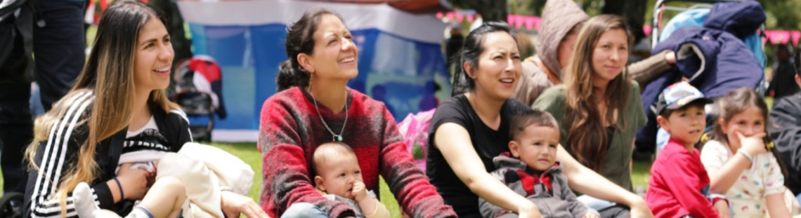 Mamás con bebés sentadas en el pasto del parque