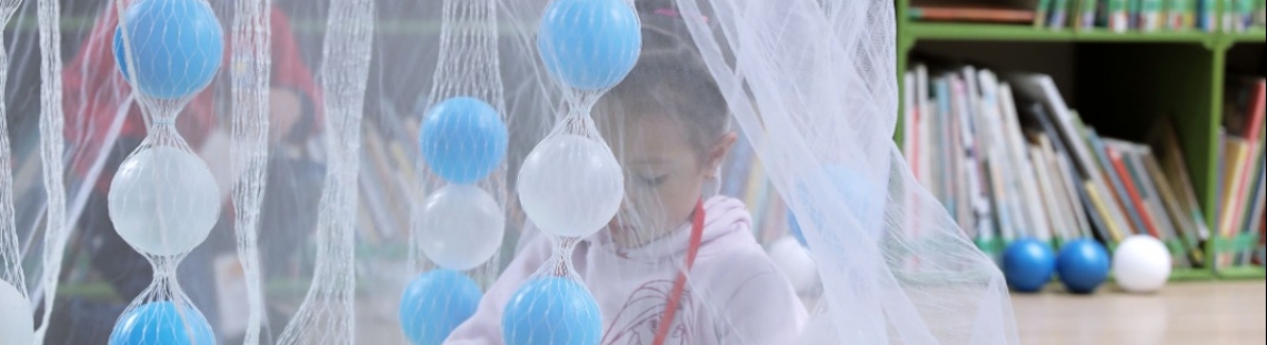 Niña jugando con red de tela blanca y pelotas