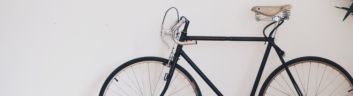 Bicicleta parada enfrente de una pared blanca. 