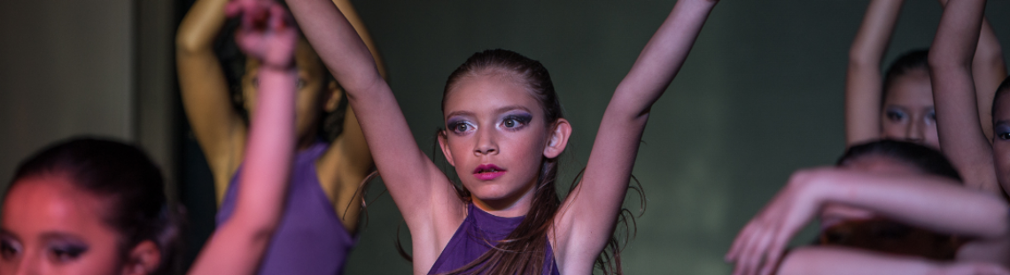 Niñas danzando con traje morado en el escenario