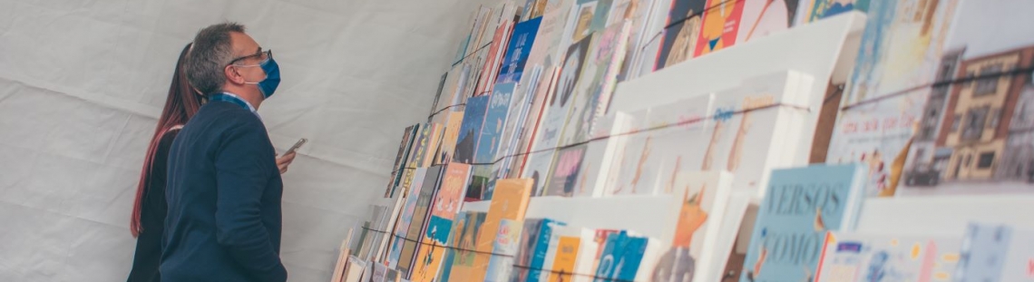 Dos personas viendo un muro con libros 