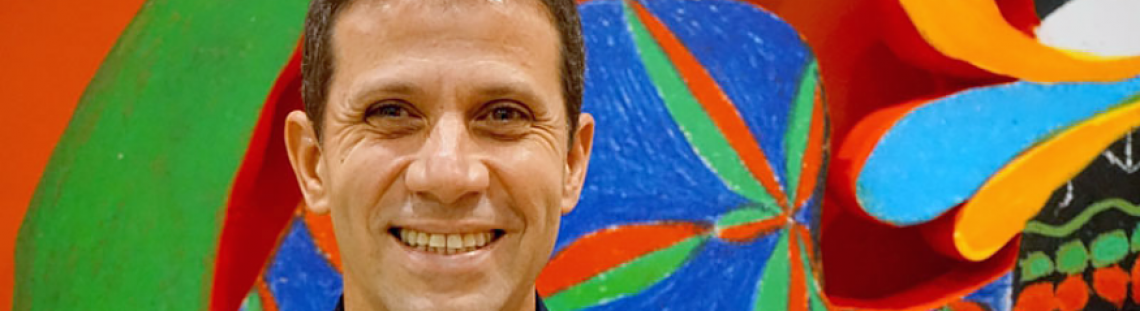 Roger Mello sonriendo con fondo de colores