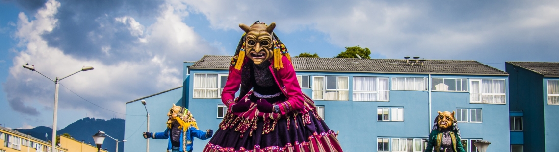 Personaje en zancos con máscara y falda en la calle