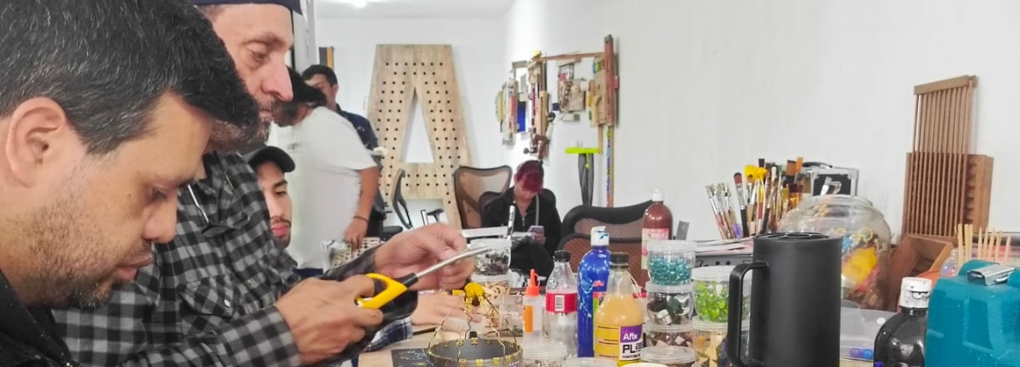 Hombres trabajando con materiales reciclados en una mesa 