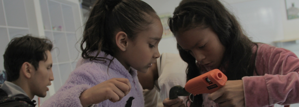 dos niñas pegan con silicona un artefacto