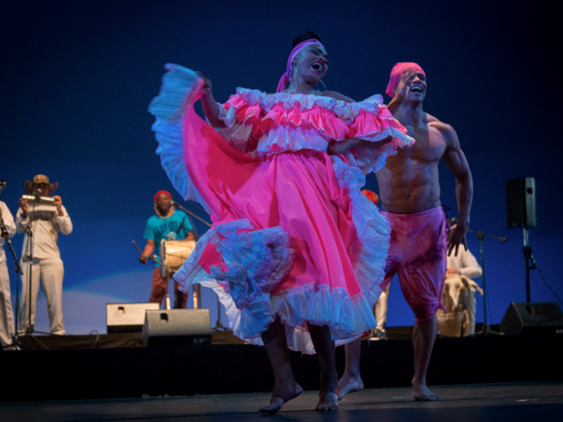 Bailarines danzando en el escenario con trajes coloridos