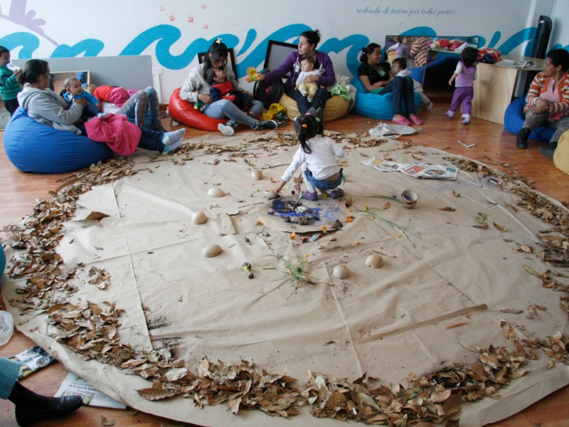 Sala de juegos con niños y madres participando en una actividad