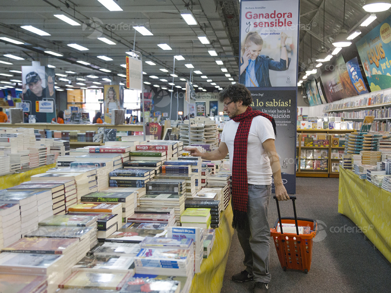 Hombre viendo libro en estand de la Feria del Libro