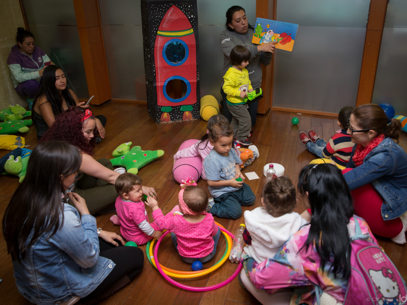 Mujeres y niños participando de una actividad lúdica e instructiva.