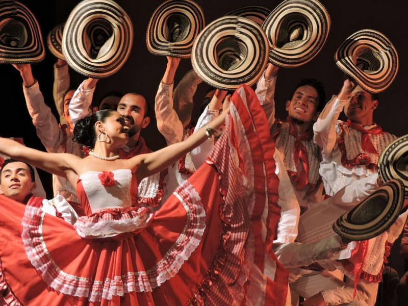 Bailarines vestidos de rojo y blanco con sombreros danzando.