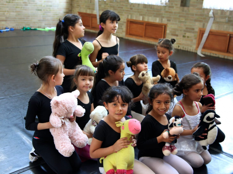 Niñas con muñecos de peluche y tela en recinto cerrado