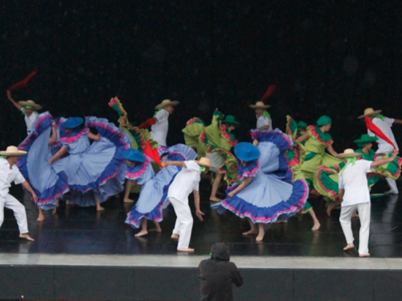 Personas danzando en el escenario con trajes coloridos.