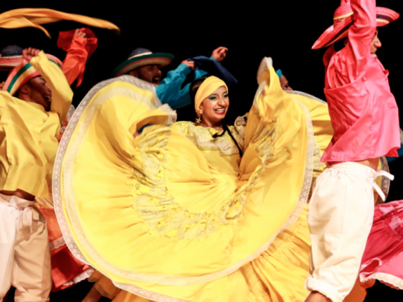 Hombres y mujeres danzando con vestidos coloridos y alegres