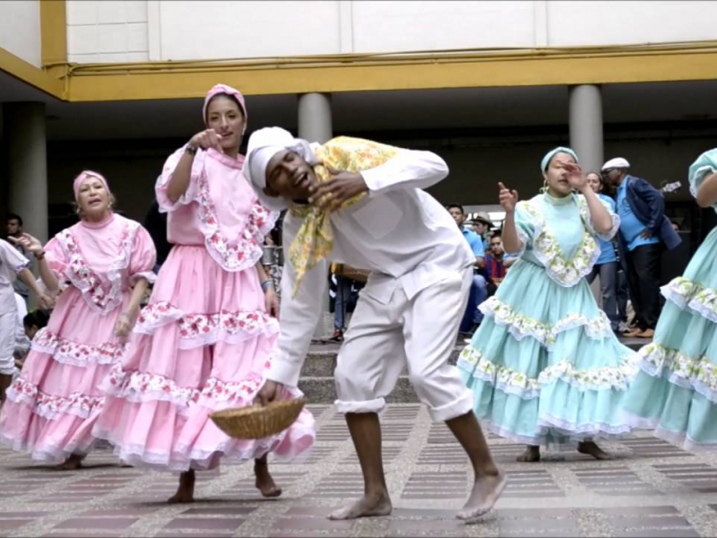 Mujeres bailando y un hombre entre ellas vestido de blanco