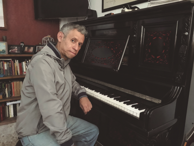 Hombre posando frente a la cámara en estudio con piano