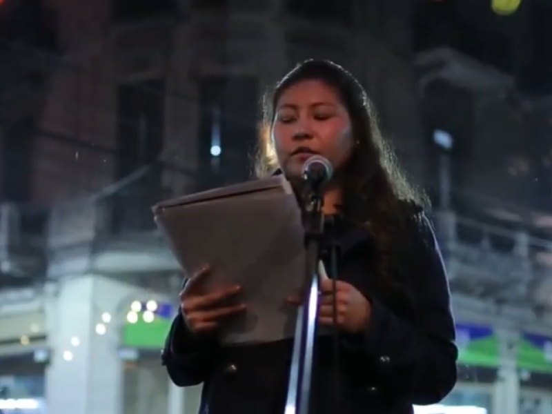 Joven mujer leyendo un texto en una calle durante la noche.