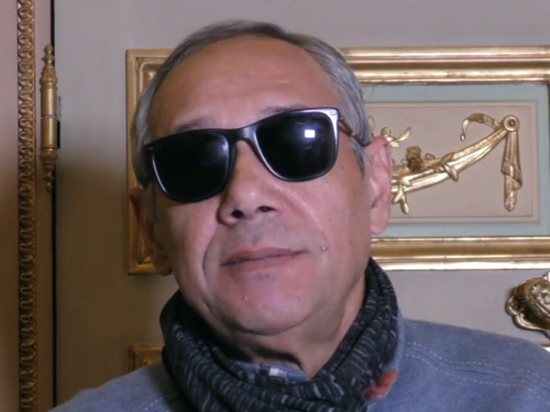 Escritor con gafas oscuras dando una entrevista - Captura de pantalla de entrevista con Casa América.