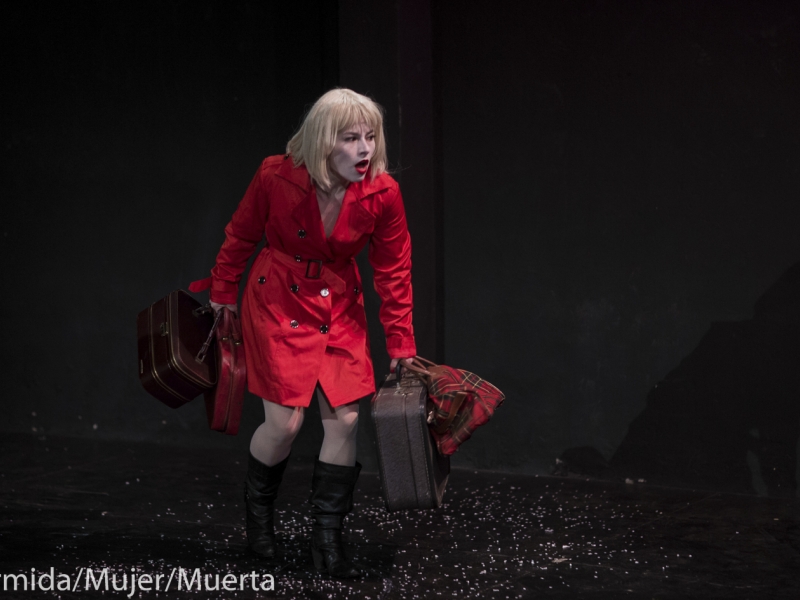 Mujer con gabardina roja y maletas en escena