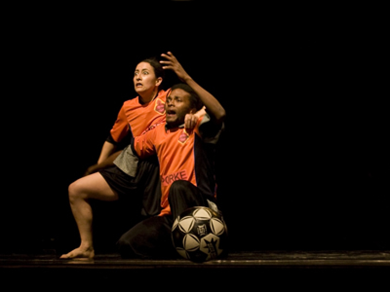 Actores en escena vestidos de jugadores con pelota de futbol