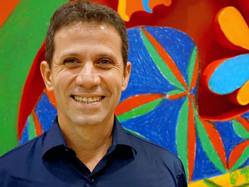 Roger Mello sonriendo con fondo de colores