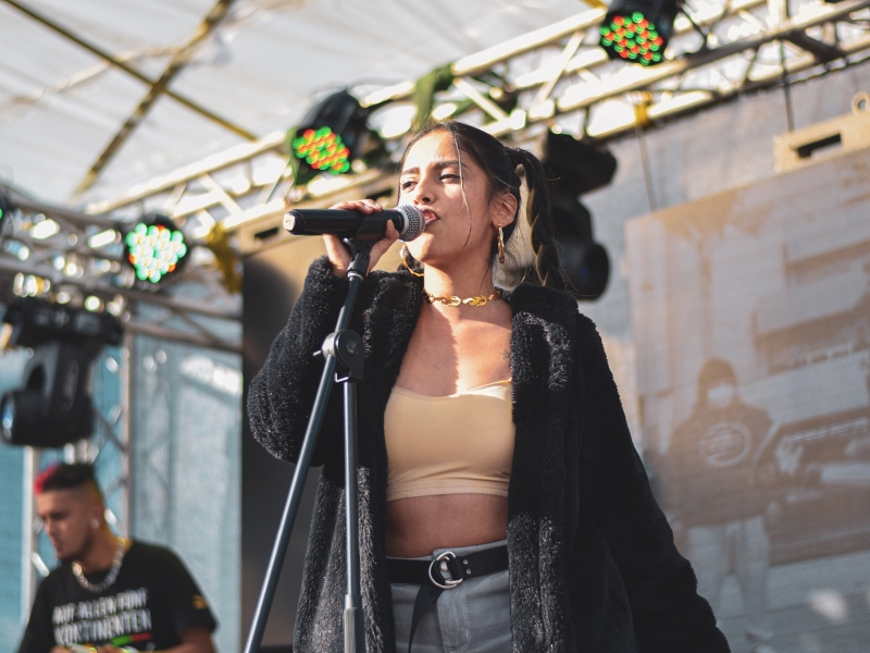 Fotografía de una mujer en escena cantando frente a un micrófono