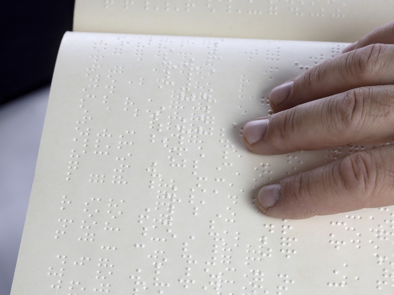 Mano sobre texto en braille. 