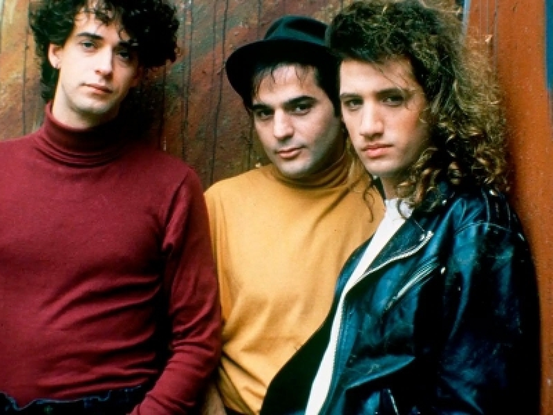 Tres integrantes de Soda Stereo enfrente de una pared. 