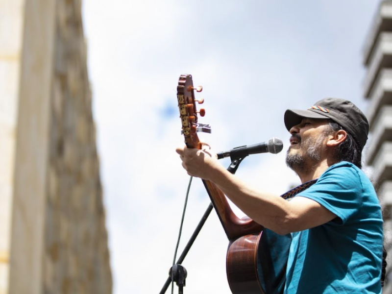 Señor con camiseta azul cantando en una tarima 