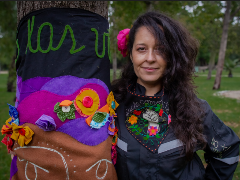 Mujer sosteniendo su bordado en un parque de día