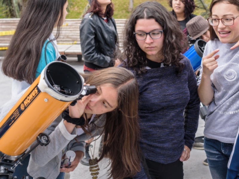 Niñas observando por telescopio. 