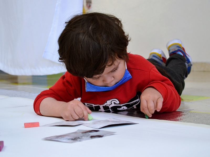 Bebé pintando sobre papel blanco acostado en el piso